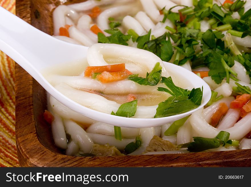 Asian noodle soup in a wooden bowl and a white spoon. Asian noodle soup in a wooden bowl and a white spoon.
