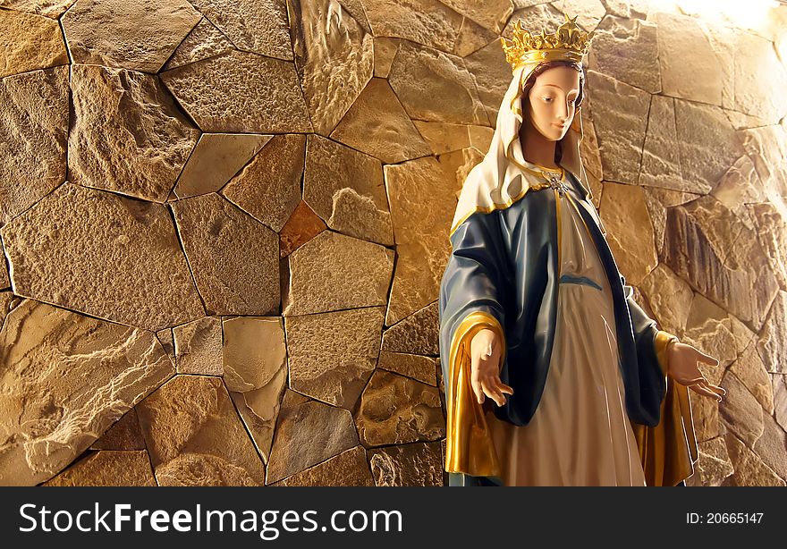 A Saint Mary statue in front of stone wall