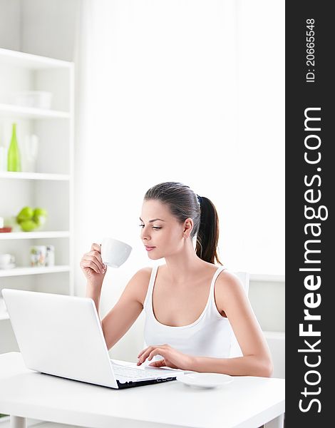 A beautiful girl with a cup and a laptop at home. A beautiful girl with a cup and a laptop at home