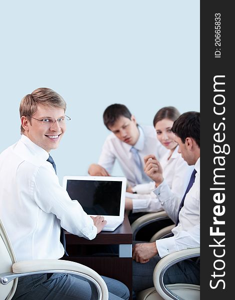 Young businessman with laptop on the background of employees in the office
