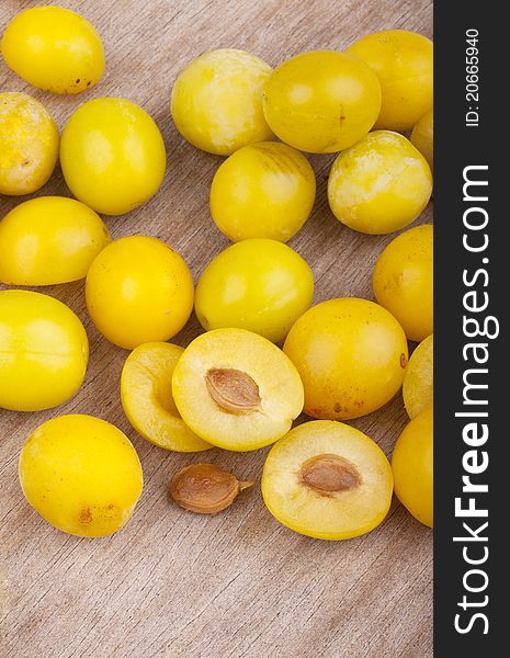 Studio-shot of small yellow plums also known as mellow mirabelles, on a wooden board.