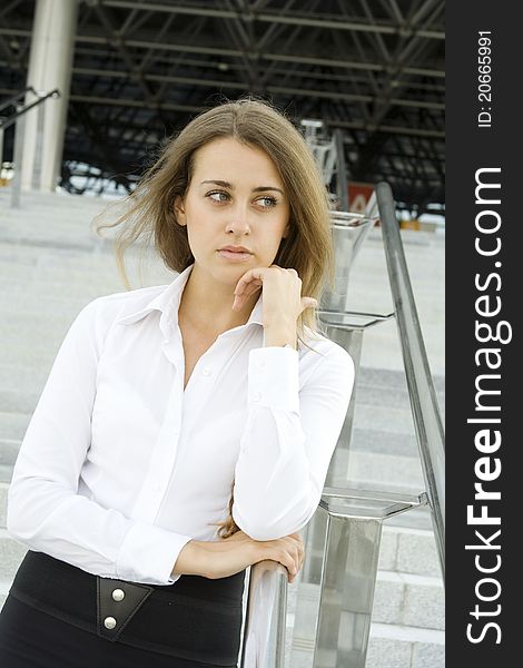 Contemporary portrait of a young professional business woman smiling on the background of the stairs and office space