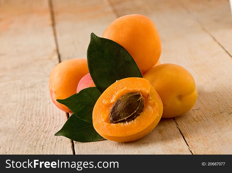 Photo of delicious tasty apricot on wooden table with leaves