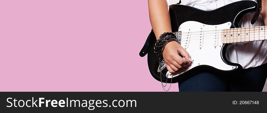 Closeup of girl playing on guitar on pink background