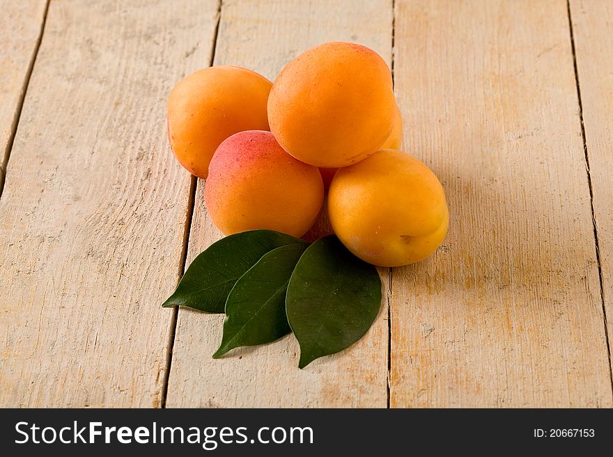 Photo of delicious tasty apricot on wooden table with leaves