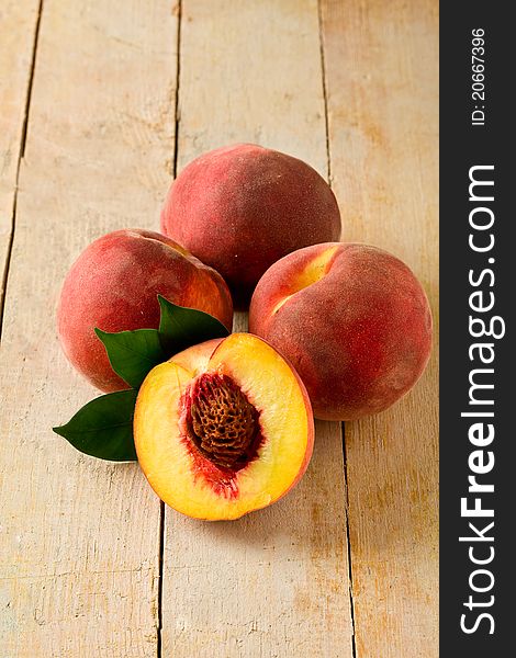 Photo of delicious peaches on wooden table with leaves. Photo of delicious peaches on wooden table with leaves