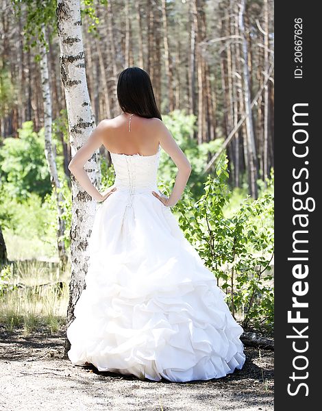 Bride with dark-brown hair posing in forest