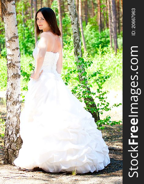 Bride with dark-brown hair posing in forest