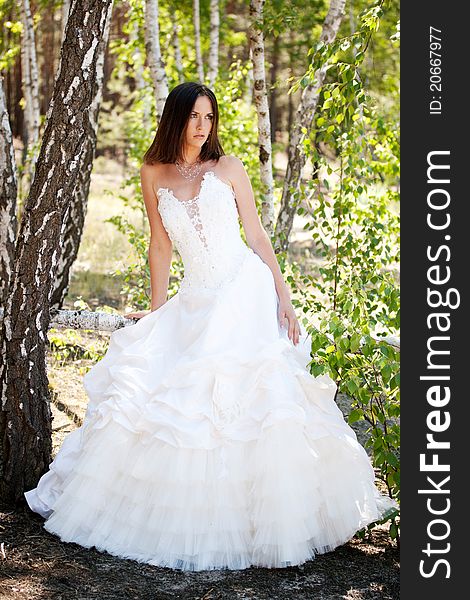 Bride with dark-brown hair posing in forest