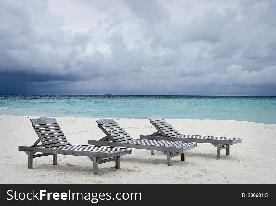Maldives Island Monsoon. Three deckchairs on the beach