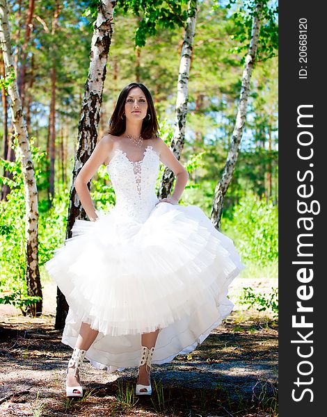 Bride with dark-brown hair posing in forest