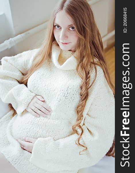 Beautiful young pregnant woman sitting on sofa