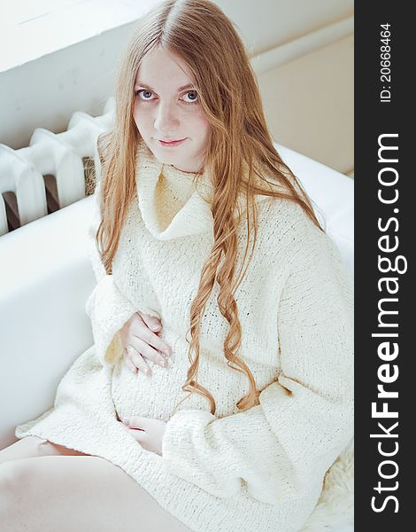 Beautiful young pregnant woman sitting on sofa