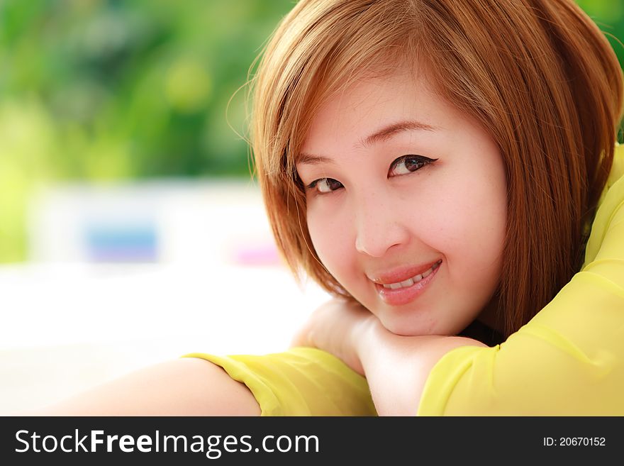 Smiling young Asian woman is sitting. Smiling young Asian woman is sitting