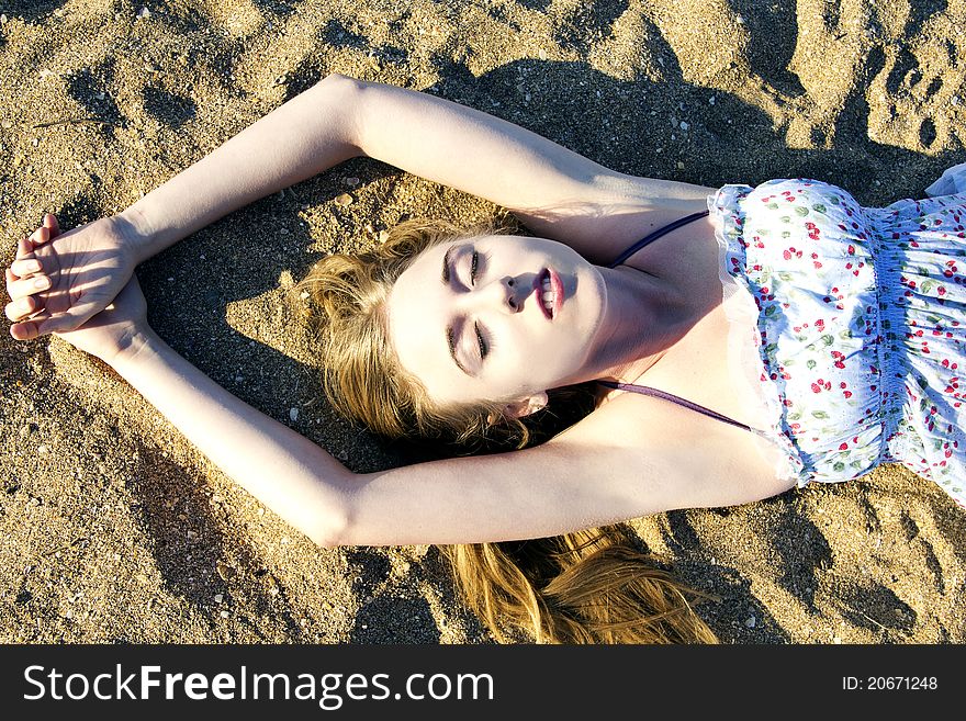 Young lady lying on the sand in the sunlight