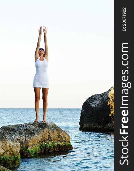 Smiling girl with arms raised towards the sky on sunny day on sunrise