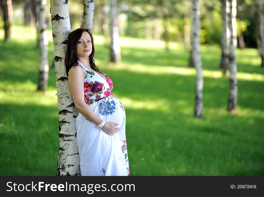 Beautiful future mom standing near tree. summer's day. Beautiful future mom standing near tree. summer's day.