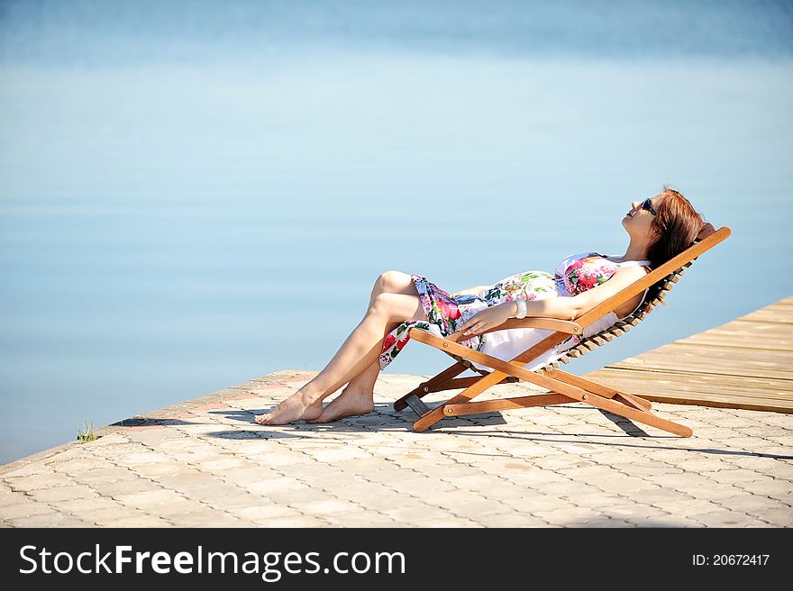 Woman sitting in lounge chair. summer's day on lakeside. Woman sitting in lounge chair. summer's day on lakeside