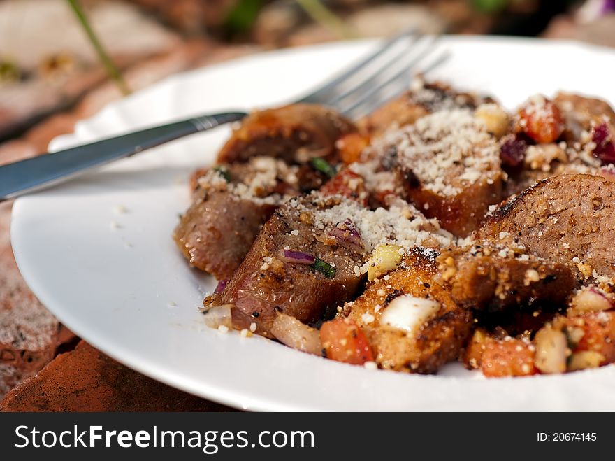 Italian sausage salads in white plate with fork on a brick background