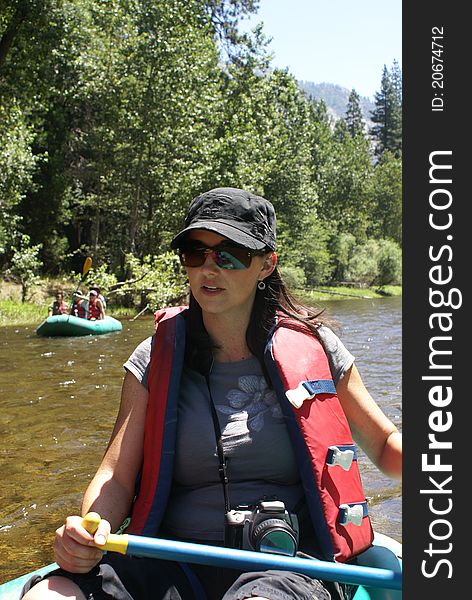 A woman wearing a life jacket or vest on a raft rowing down the Merced river in Yosemite National Park, USA. A woman wearing a life jacket or vest on a raft rowing down the Merced river in Yosemite National Park, USA