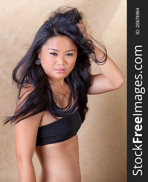 A portrait of a gorgeous young Asian woman in a black bandeau top, with her hair blowing messily. A portrait of a gorgeous young Asian woman in a black bandeau top, with her hair blowing messily