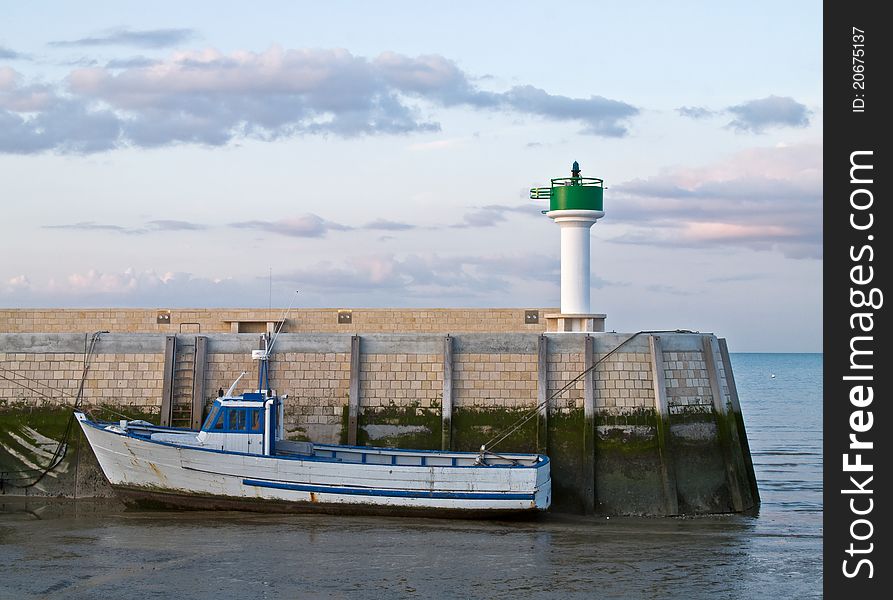 Small fishing boat anchored at low tide at a docking station of a small fishing port on the island of ile de re,france.