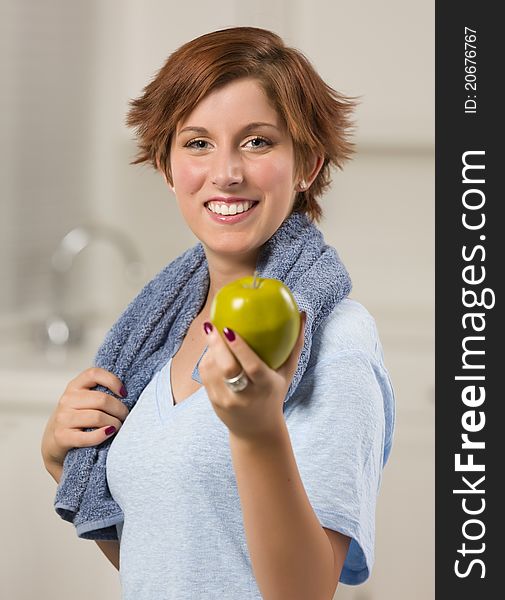 Pretty Red Haired Woman with Towel Holding Green Apple in Her Kitchen. Pretty Red Haired Woman with Towel Holding Green Apple in Her Kitchen.