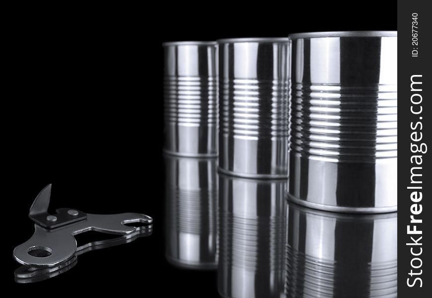 Three tin cans and an opener over a black background. Three tin cans and an opener over a black background.