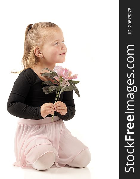 A beautiful preschooler kneeling with a pink flower while in her ballerina outfit. A beautiful preschooler kneeling with a pink flower while in her ballerina outfit.