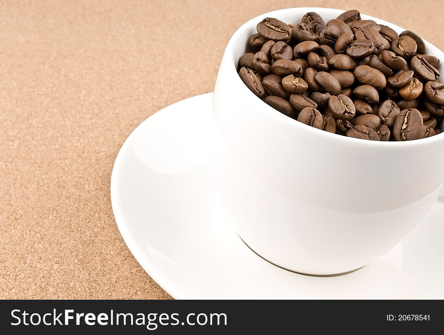 Close coffee cup filled with coffee beans on textured background
