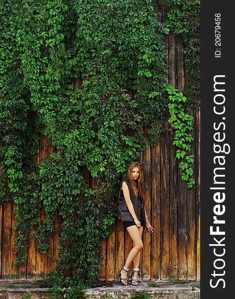 Fashion shot of a beautiful model posing at the vineyard wall