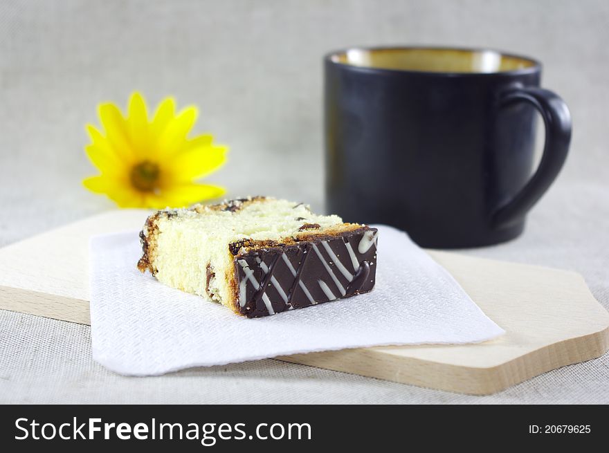 A piece of sliced cake and a cup of coffe. Decorated with yellow flower. A piece of sliced cake and a cup of coffe. Decorated with yellow flower