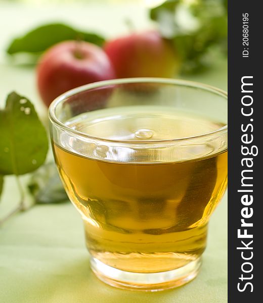 Glasses of apple juice with apples on the background.