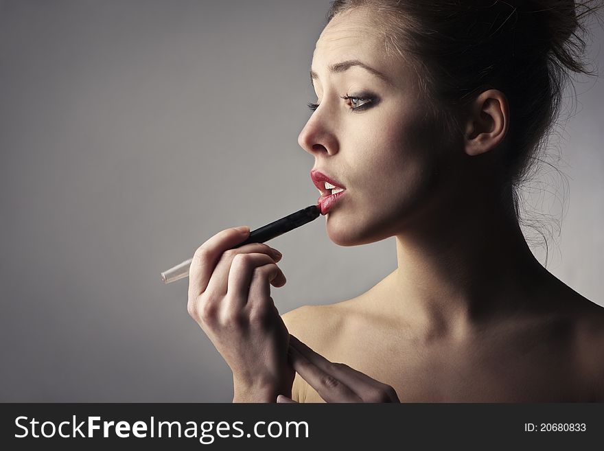 Beautiful woman putting on some lipstick