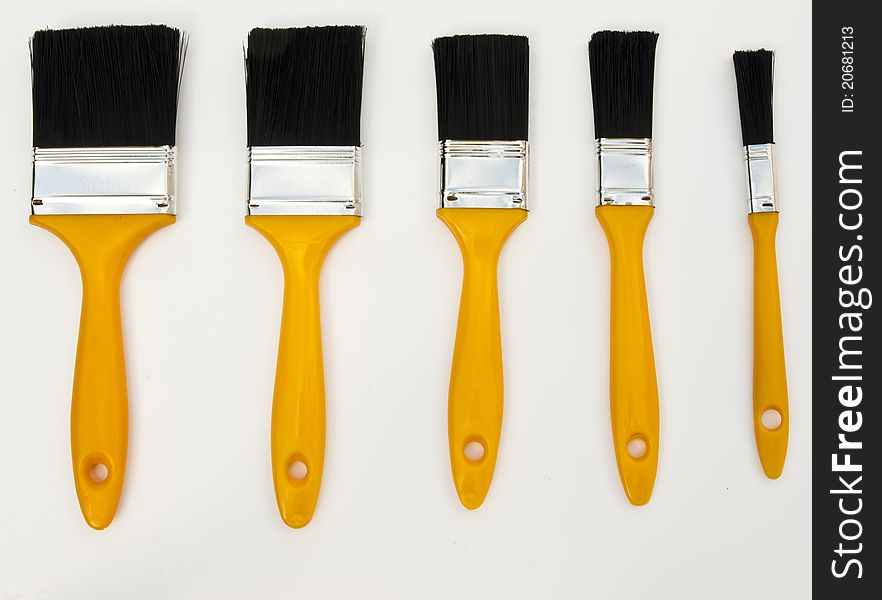 Five yellow handled new different sized paint brushes. Five yellow handled new different sized paint brushes