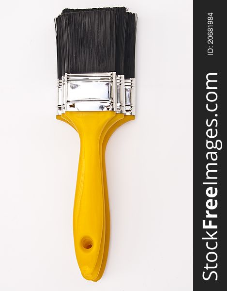 Three new yellow paint brushes stacked on top of each other on a white background. Three new yellow paint brushes stacked on top of each other on a white background