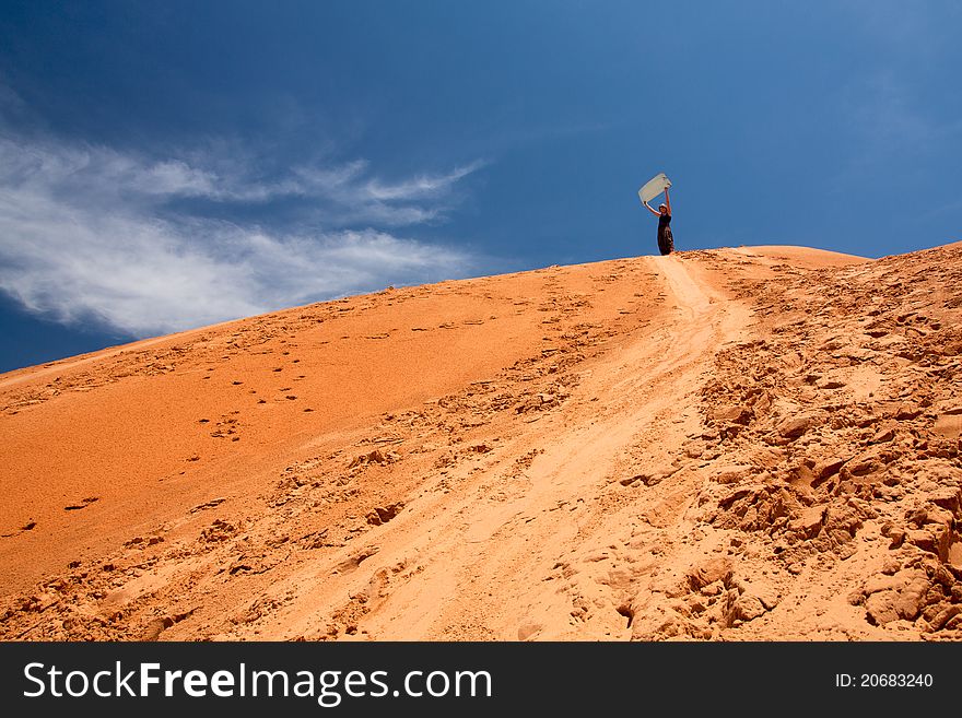 Woman standing on top of the sand dunne, with slideboard in her hands. Mui Ne - Vietnam (Red dunnes). Woman standing on top of the sand dunne, with slideboard in her hands. Mui Ne - Vietnam (Red dunnes)