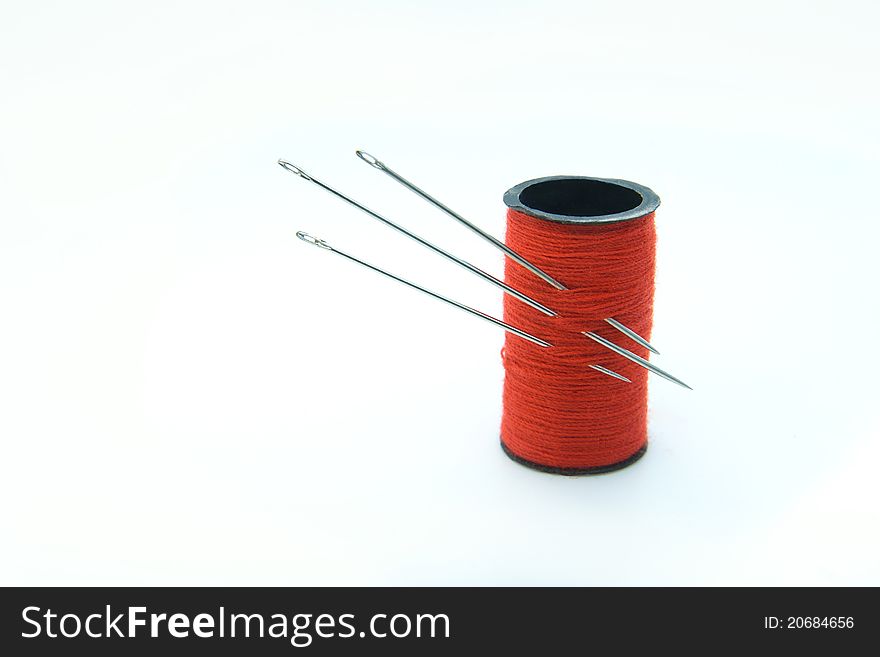 Three sharp metal needles in the bobbin with red thread. Three sharp metal needles in the bobbin with red thread