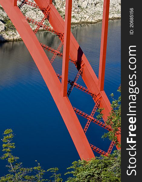 Red Maslenica bridge, blue water, white rocks and the green tree. Red Maslenica bridge, blue water, white rocks and the green tree