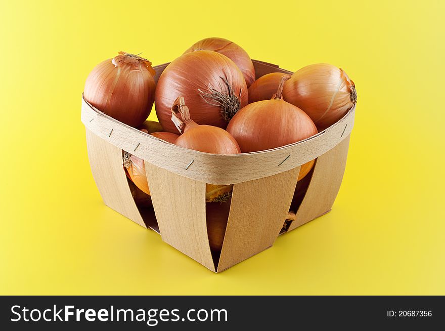 Onions in a box on yellow background. Onions in a box on yellow background.