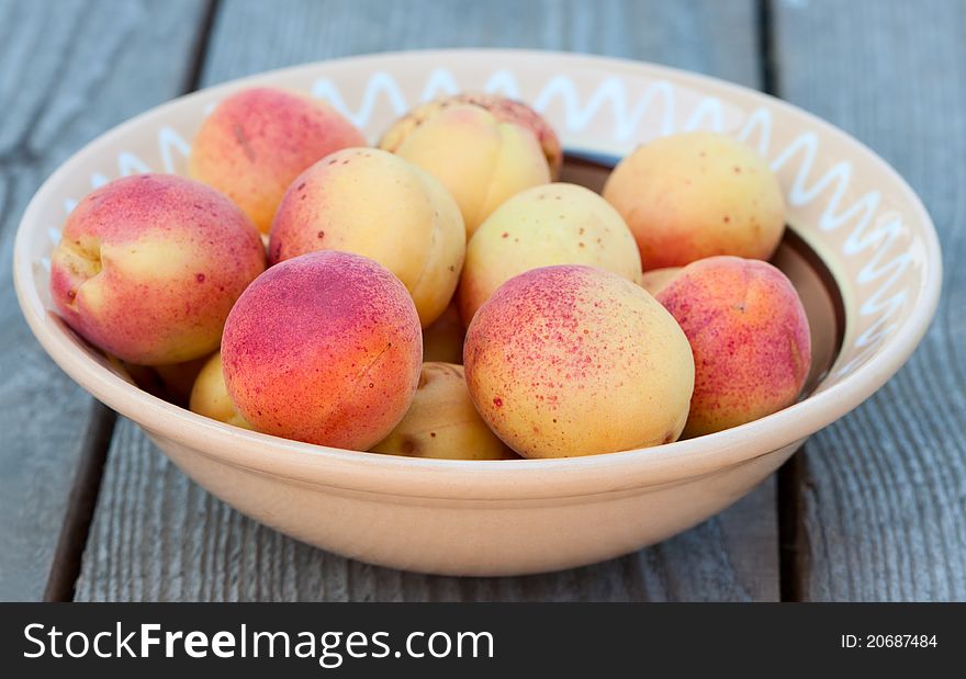 Apricots on the plate on a wooden table. Apricots on the plate on a wooden table.