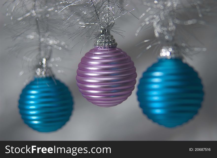 Three metallic Christmas ornaments hanging on tree