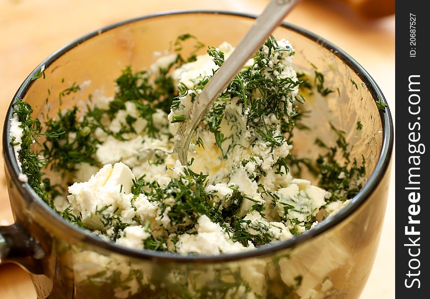 In a glass dish is a mixture of feta cheese and dill. In the circle sticking a spoon. Cheeses mashed. In a glass dish is a mixture of feta cheese and dill. In the circle sticking a spoon. Cheeses mashed.