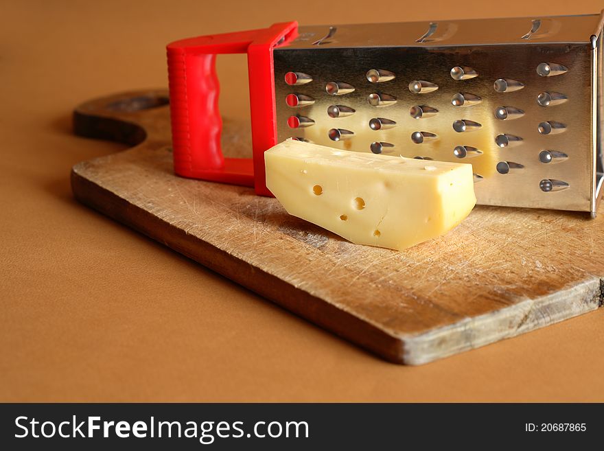 Piece of cheese on wooden cutting board near. Piece of cheese on wooden cutting board near