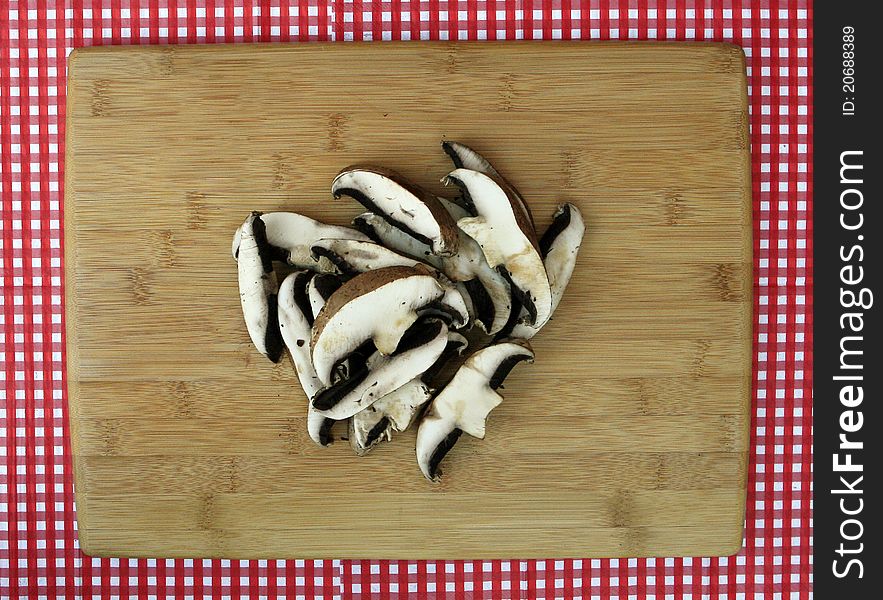 Fresh Sliced Portabella Mushrooms on Clean Cutting Board isolated on red and white checkered background. Fresh Sliced Portabella Mushrooms on Clean Cutting Board isolated on red and white checkered background