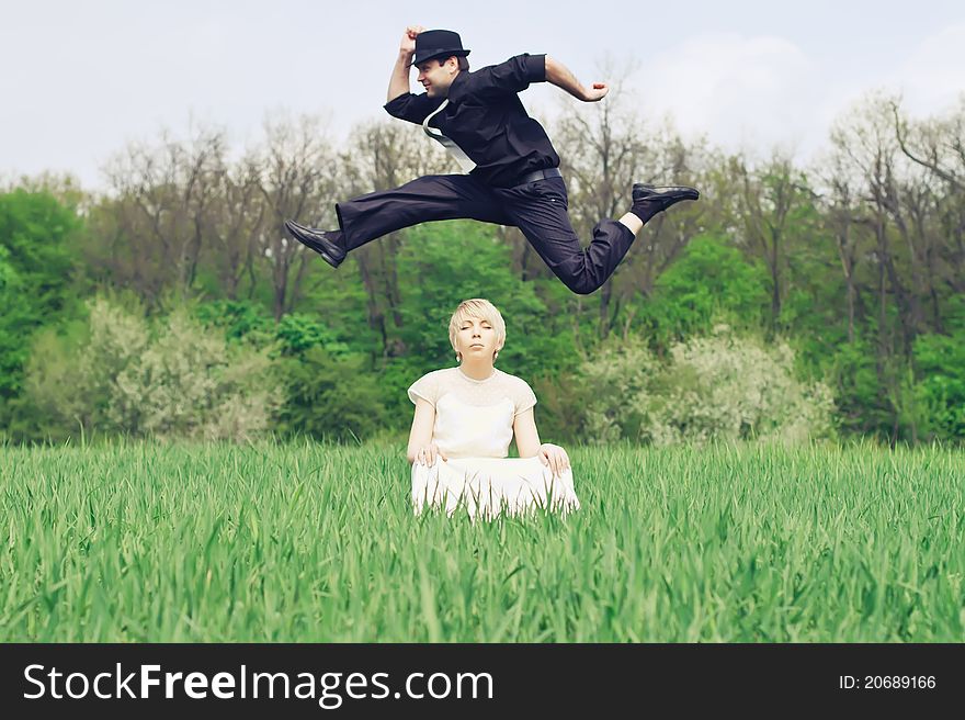 Young couple, dressed in retro style. Groom jumping over the head of bride.