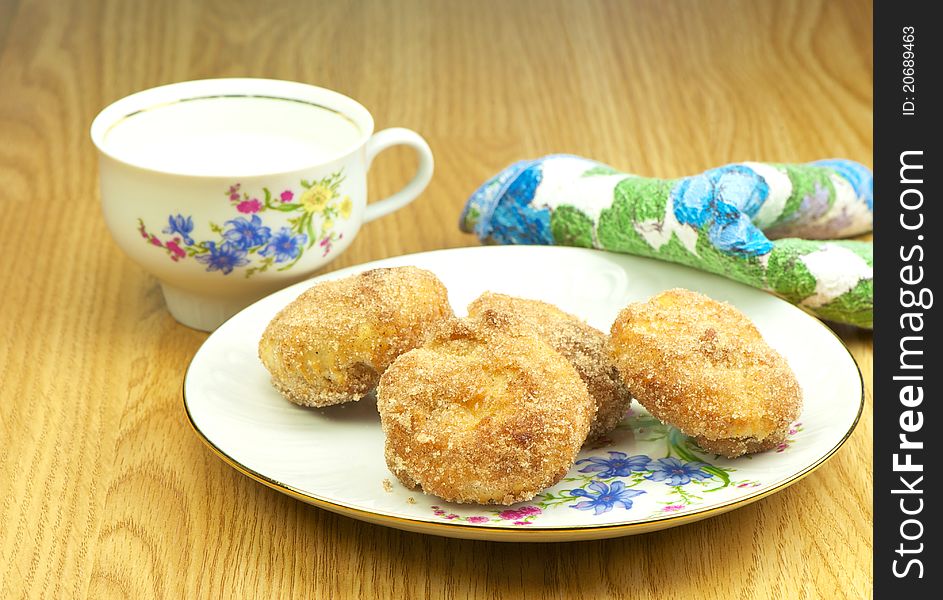 Close up image of a plate of delicious homemade nutmeg muffins rolled in cinnamon sugar with a cup of milk. Close up image of a plate of delicious homemade nutmeg muffins rolled in cinnamon sugar with a cup of milk.