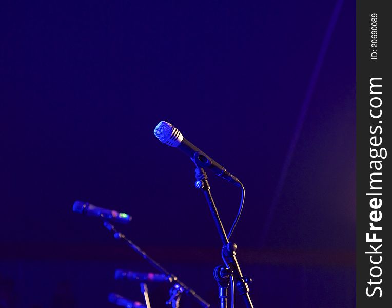 A row of microphones on a concert scene in blue spotlight