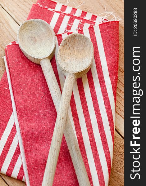 Two wooden spoons rest on a red striped kitchen towel. Two wooden spoons rest on a red striped kitchen towel.