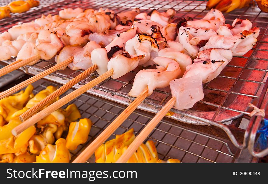 Grilled squids in group with wooden stick on grill. Grilled squids in group with wooden stick on grill